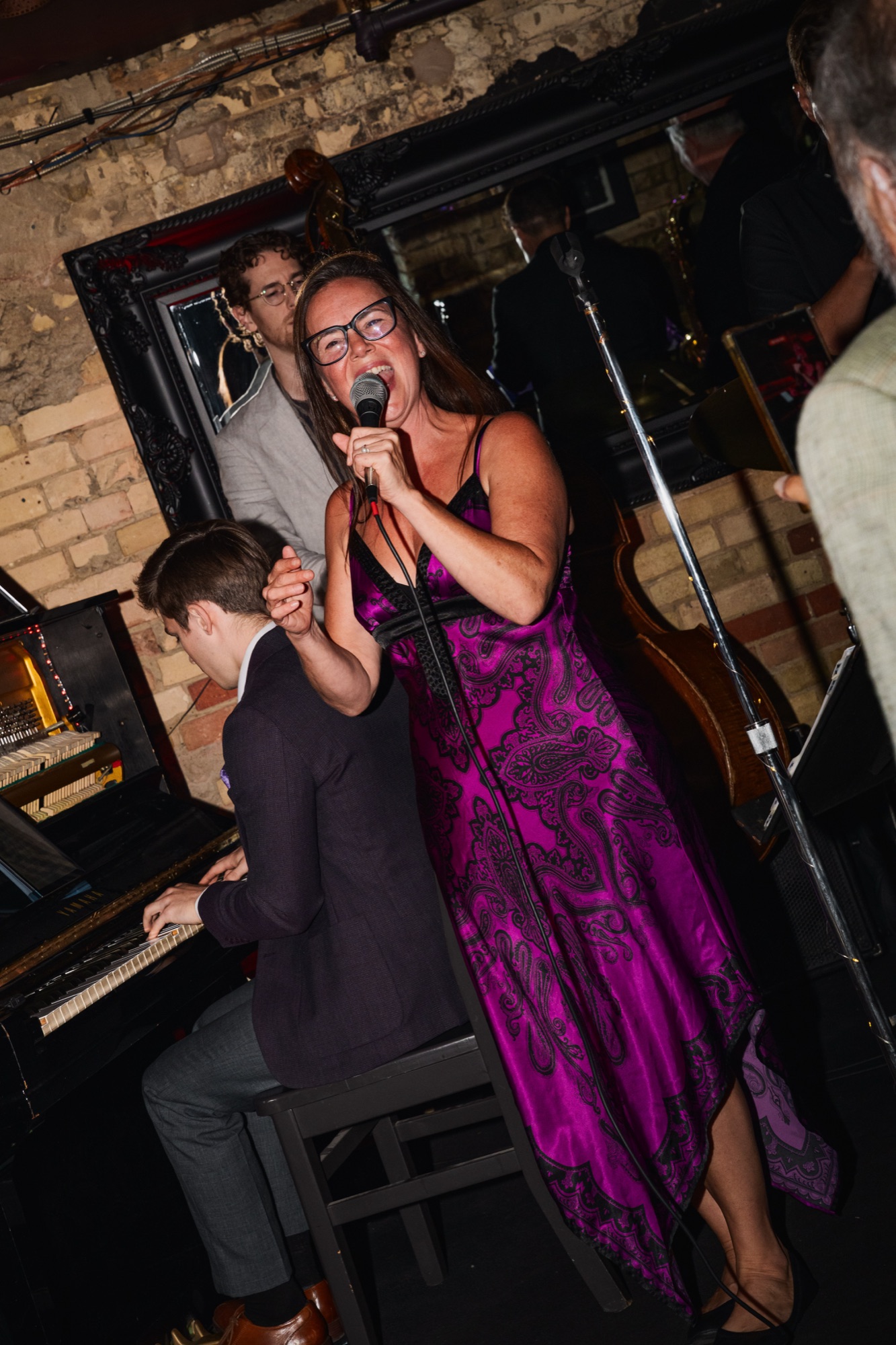A singer performing with piano and upright bass behind her