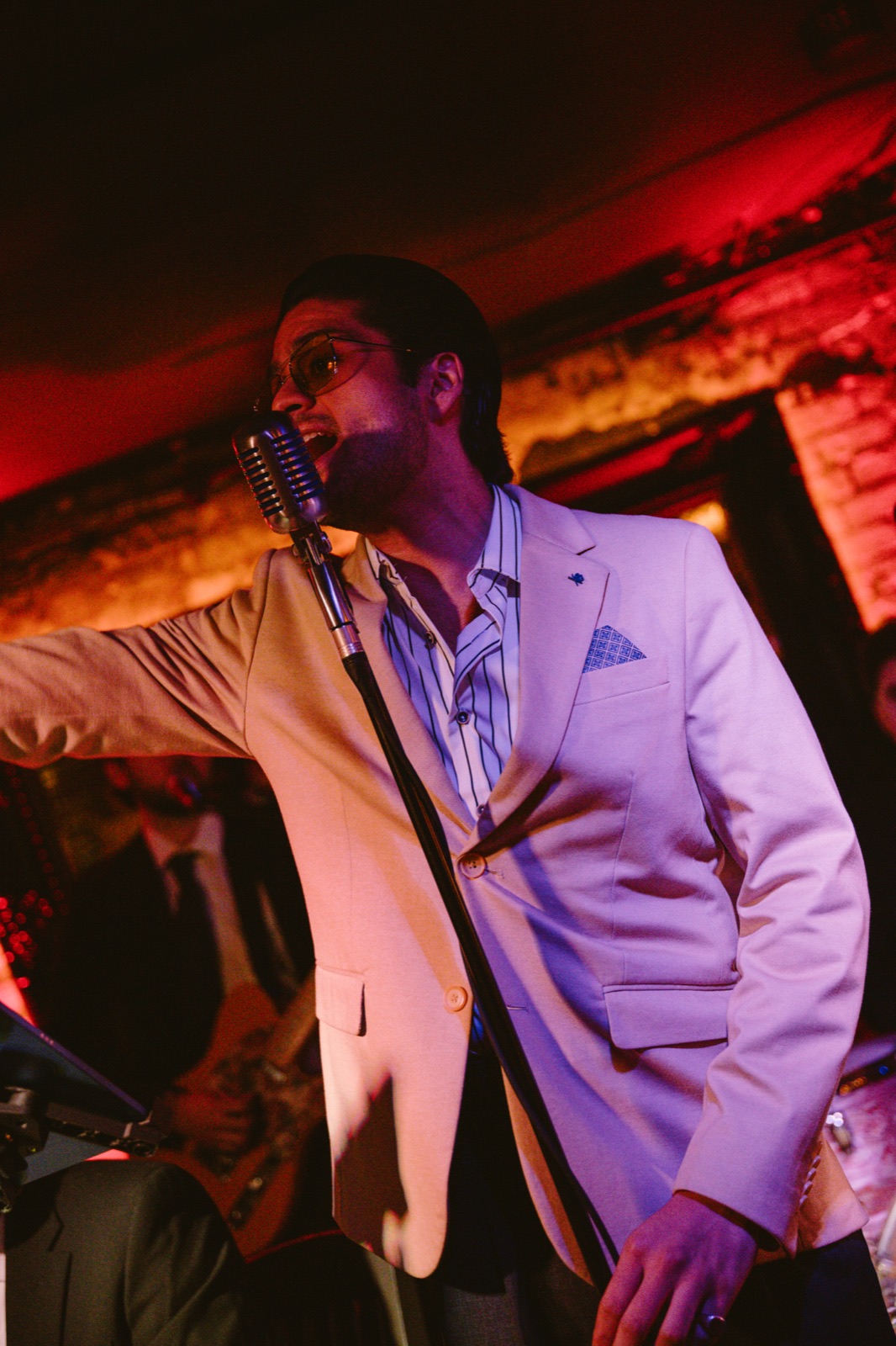 A singer in a cream jacket at a vintage microphone