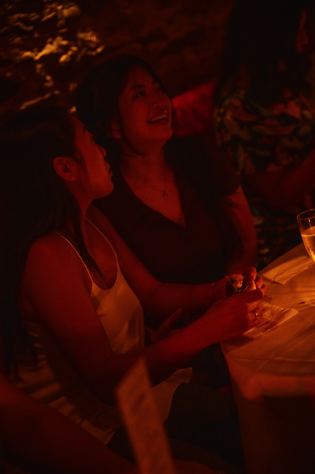 Two guests laughing together at a candlelit table