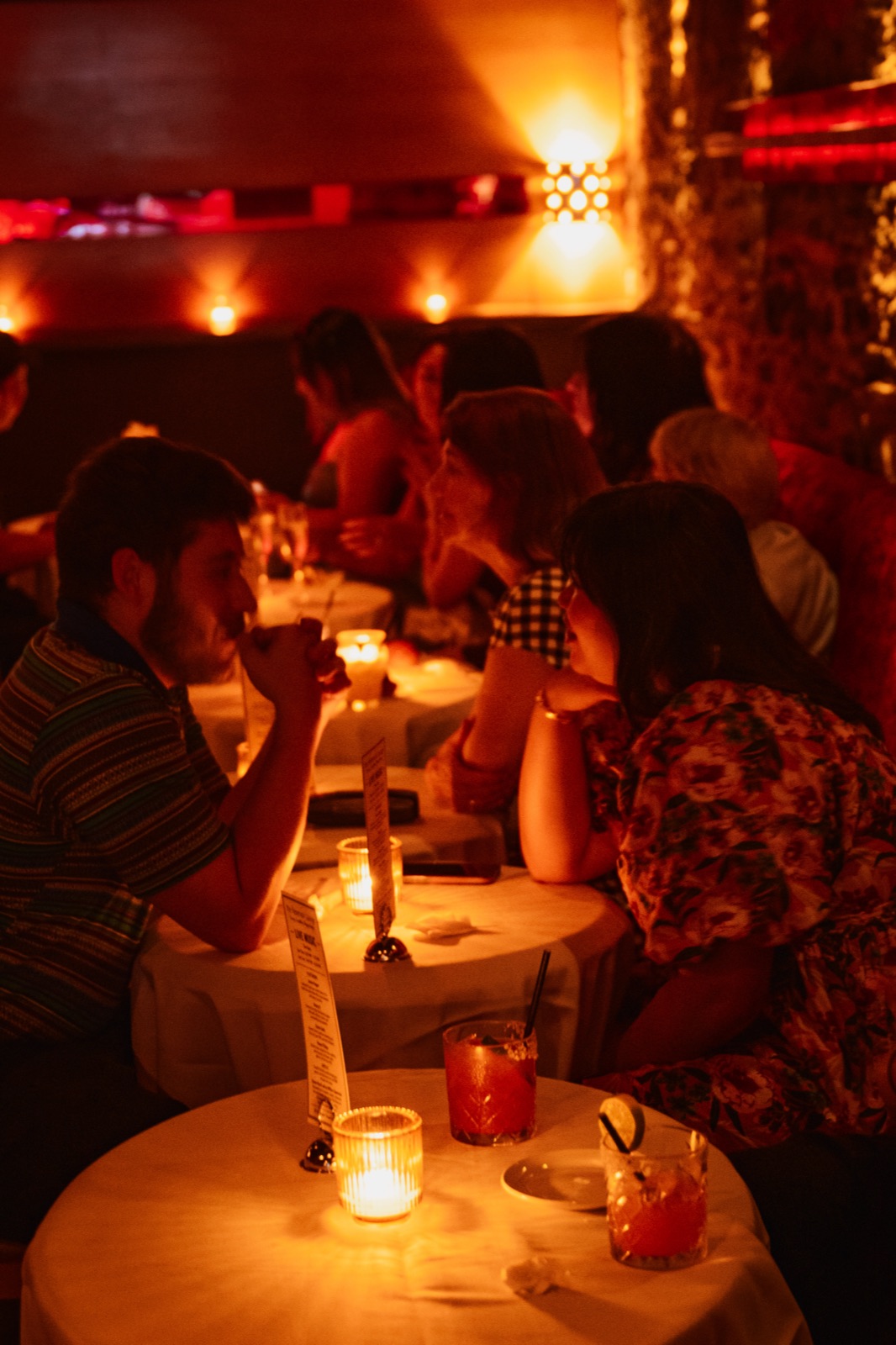 Guests at candlelit tables with cocktails on a weekend night