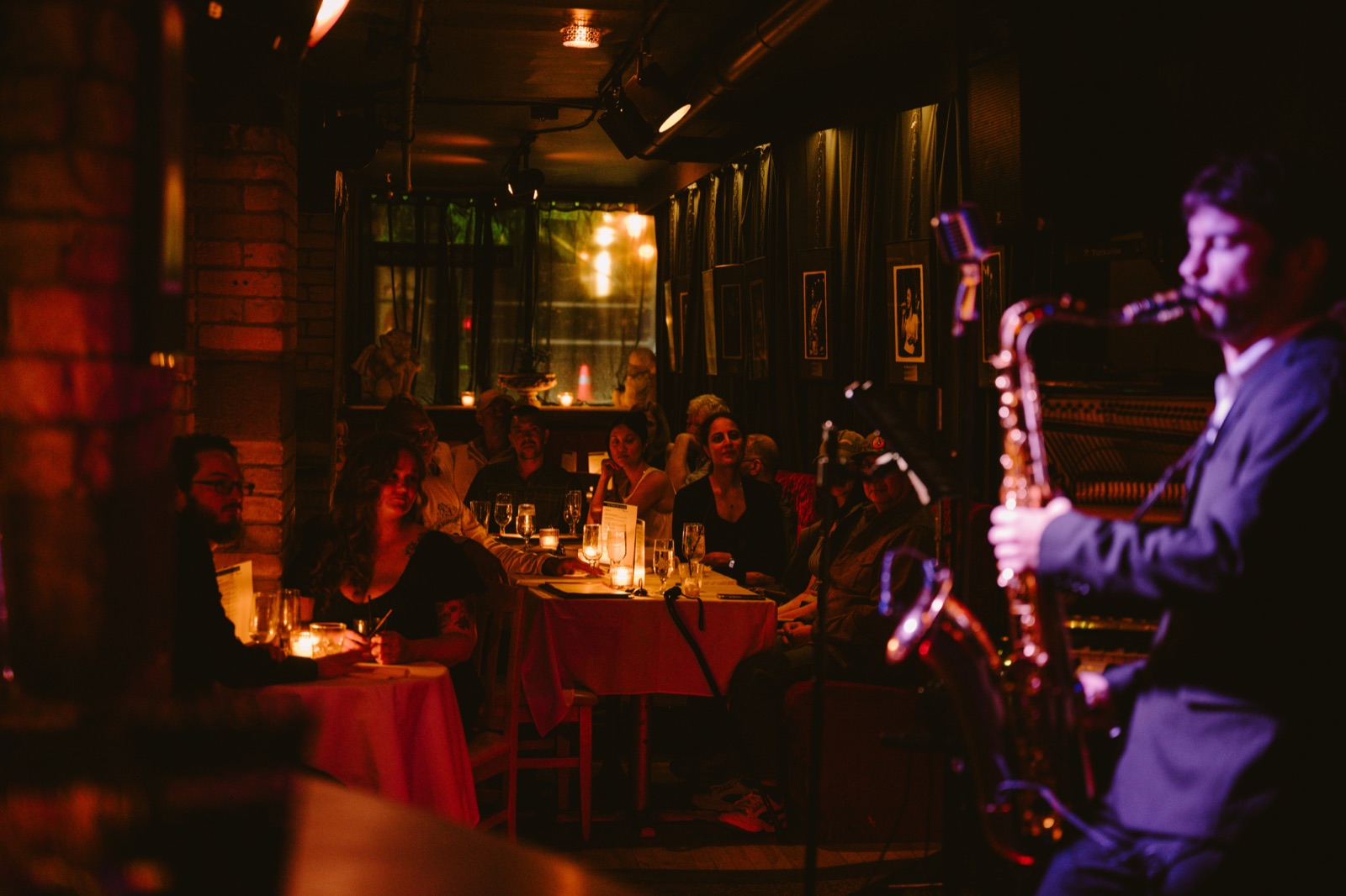 A saxophone player performing beside candlelit tables