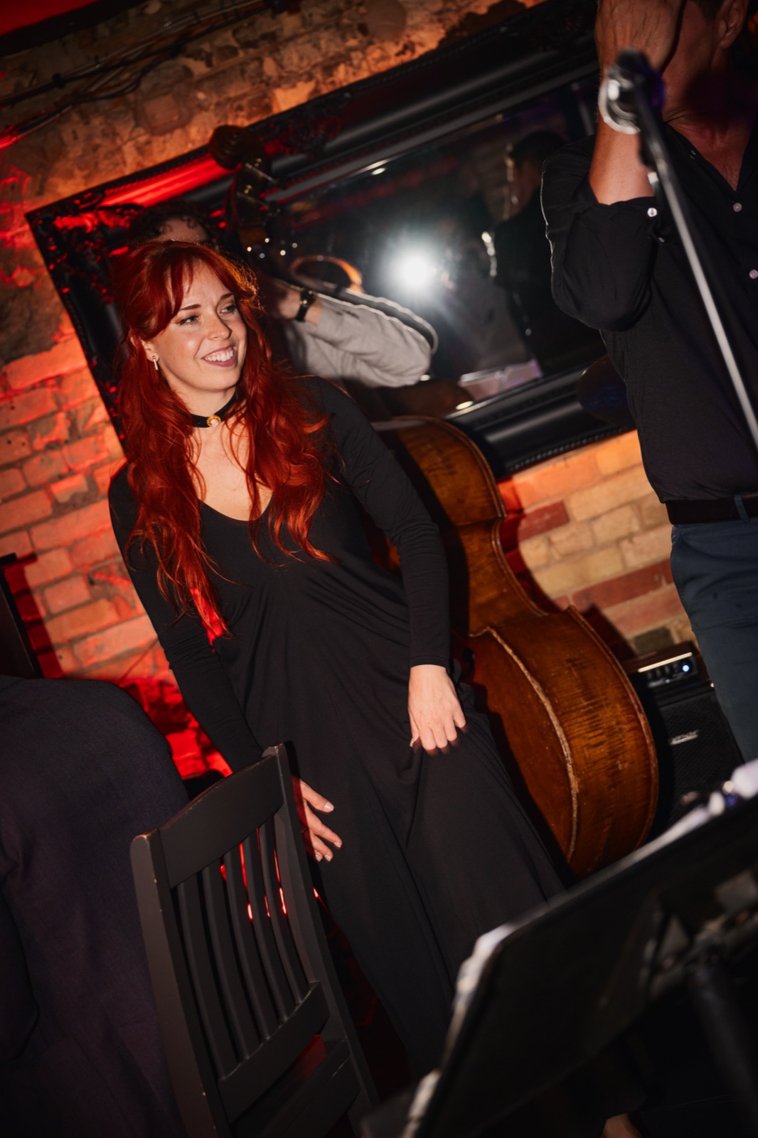 A singer smiling on stage beside an upright bass