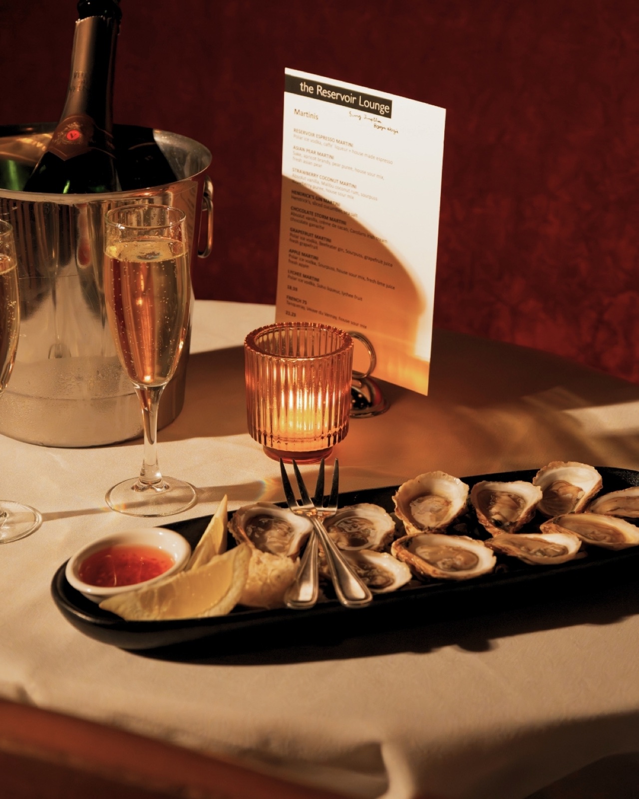 A tray of fresh oysters beside champagne on ice