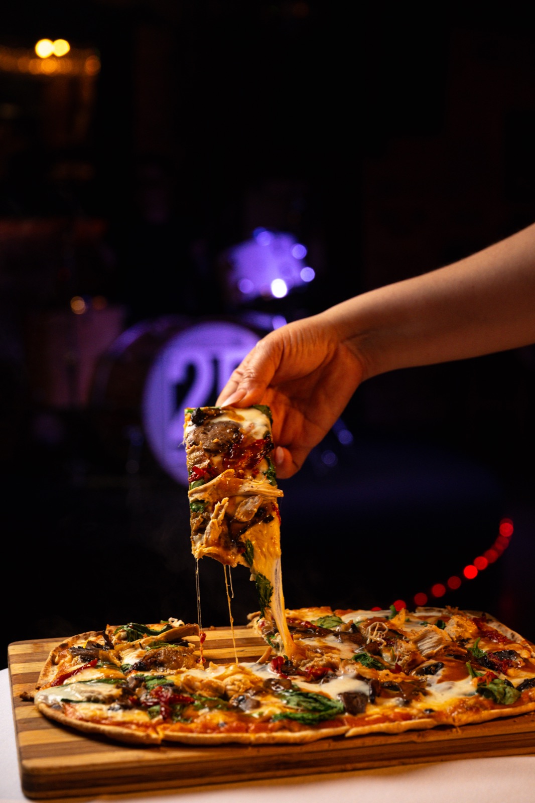 A slice being lifted from a crispy thin-crust pizza